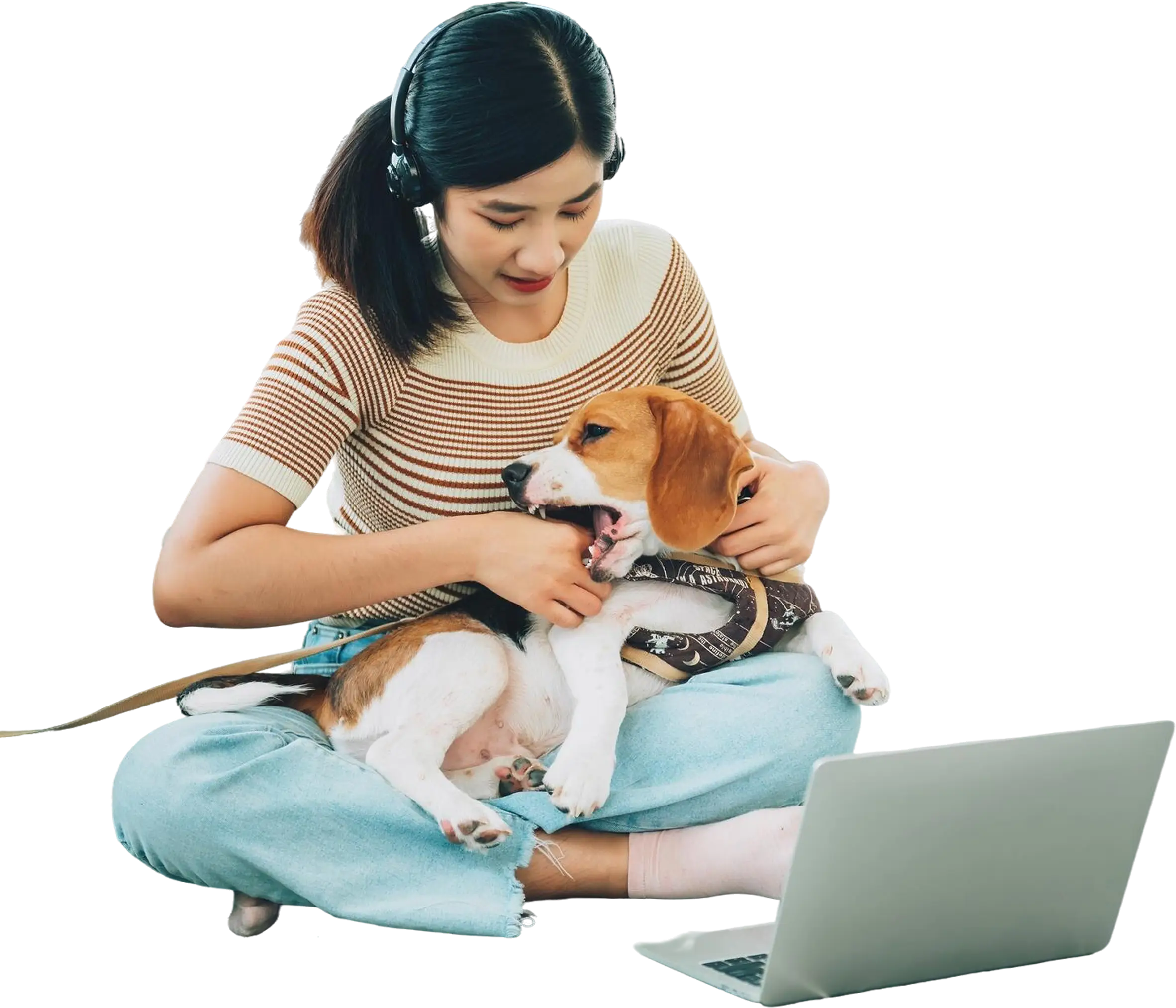 Pet owner holding a dog while working on a laptop